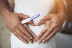 pregnant_woman_her_husband_hand_showing_heart_shape-37021288